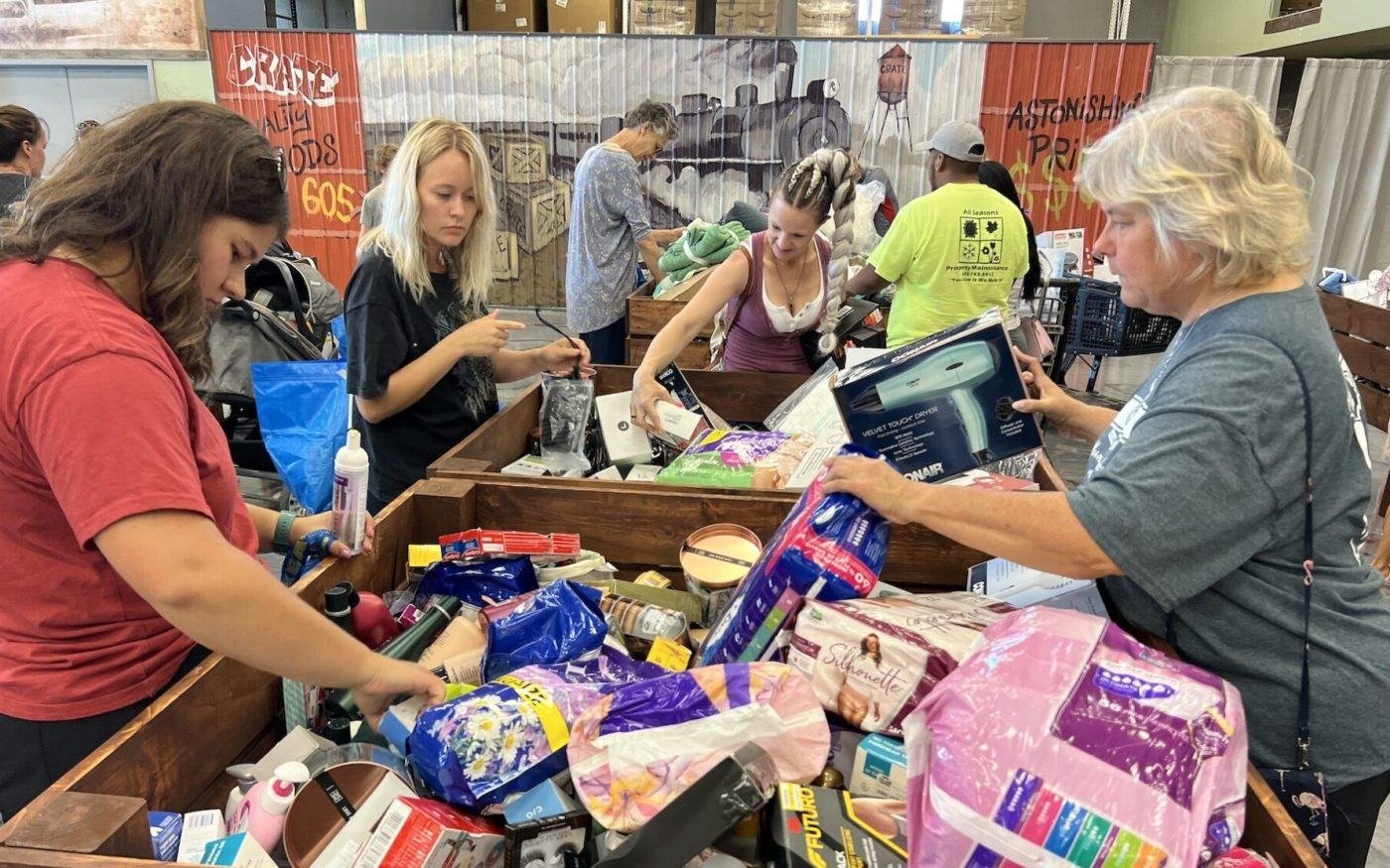 Shoppers reaching into a bin of health and beauty products at Amazing Stock